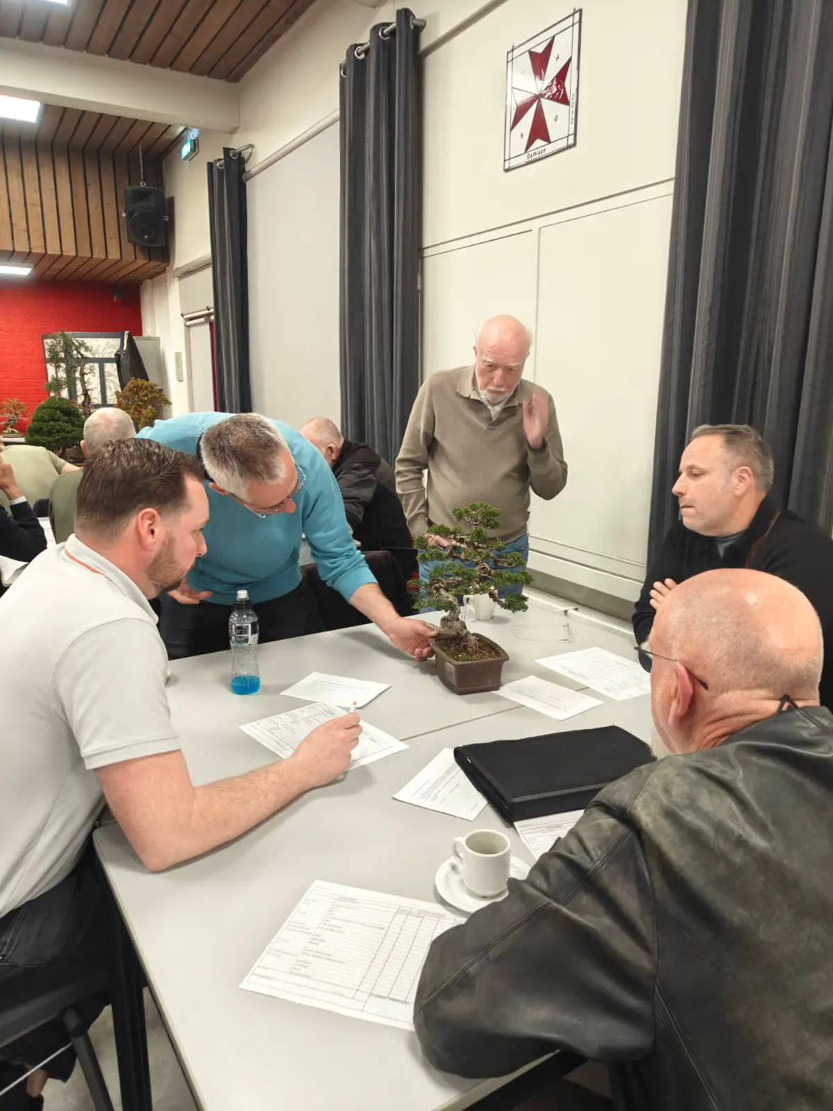 Leden bespreken samen een bonsai tijdens een clubavond